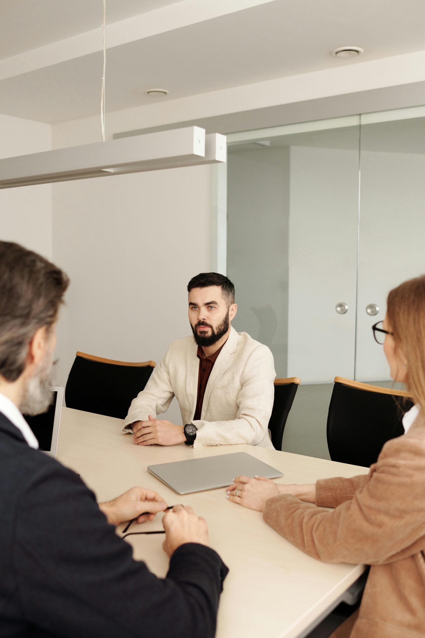 Three professionals engaged in a business meeting around a table in a modern office setting.